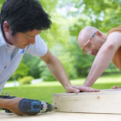 two men assembling frames for cornhole game board