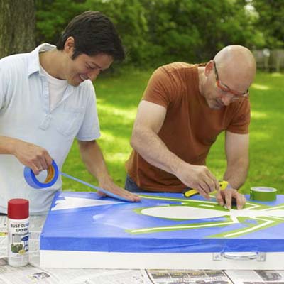 two men taping off design for cornhole game board