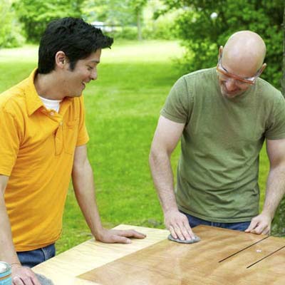 people applying the buff and finish coats while building a ricochet game board