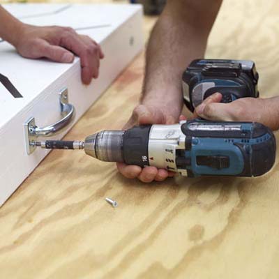 two men attaching utility pulls for cornhole game board