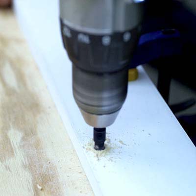 people drilling holes in the sides of the boards while building a ricochet game board