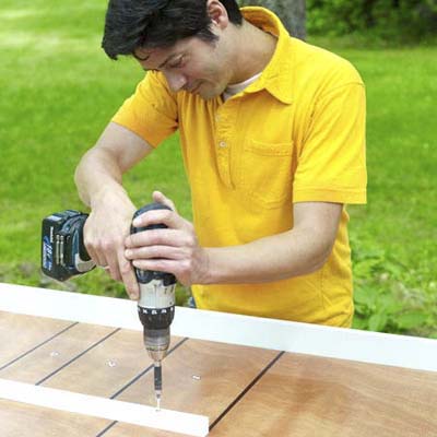 people attaching the center rail while building a ricochet game board