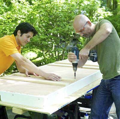 people attaching the leg supports while building a ricochet game board