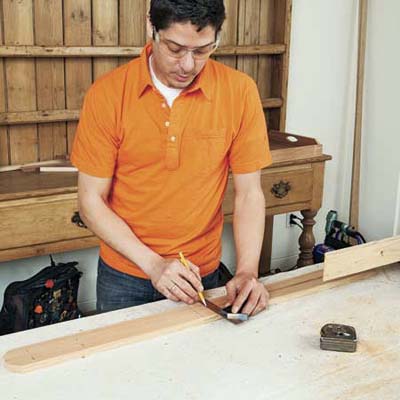 Mark Powers marks notch locations on the leg pieces of a bar cart