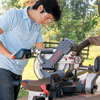 Mark Powers uses a compound miter saw to cut the tree branch leg pieces
