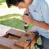 Mark Powers drills pilot holes for the tree bench leg pieces