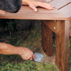 Mark Powers uses a garden spade to dig away under the bench legs to make the bench level
