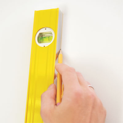 hands using a level to transfer the lines to the wall for the painted stripes