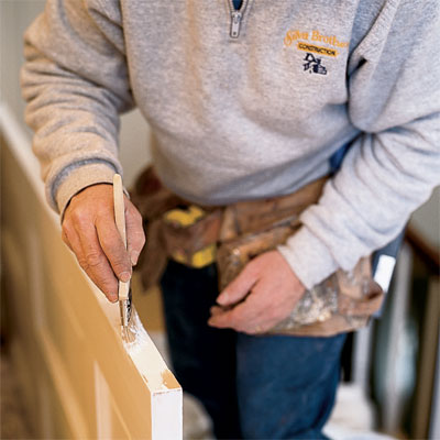 hands priming and painting the newly exposed parts of the door