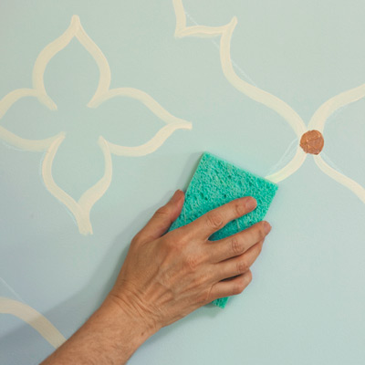 man using sponge to erase chalk line after painting wall design