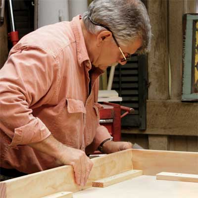 Tom Silva attaches an apron to the table top for a trestle table