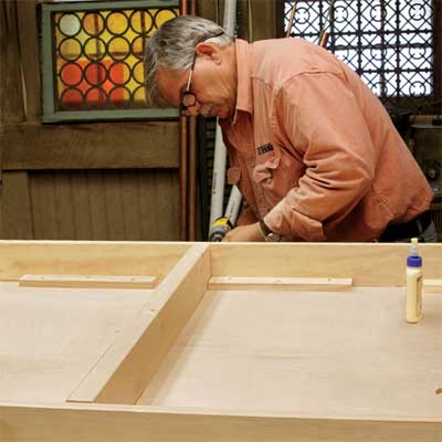 Tom Silva attaches stringers to the table top for a trestle table