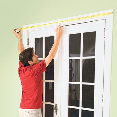 Mark Powers measures the top casing above a set of French doors