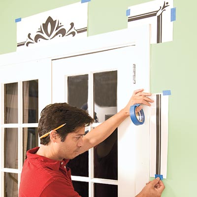 Mark Powers tapes a printout of the stencil pattern around the French doors for reference