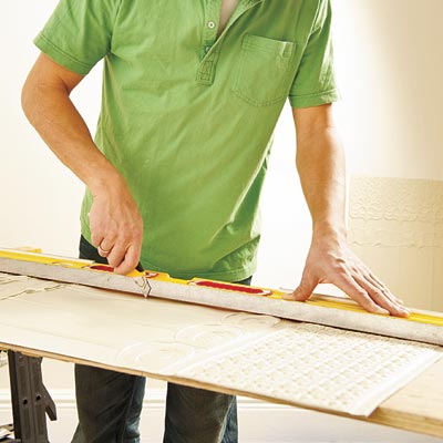 using a straightedge and utility knife to cut the first Lincrusta wainscot panel