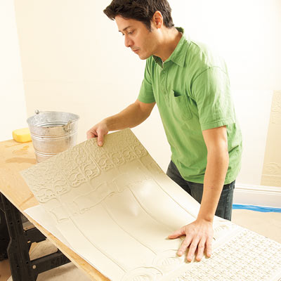 using a sponge and warm water to soak the back of a Lincrusta wainscot panel