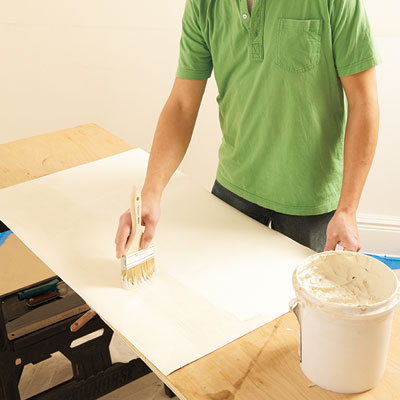 applying adhesive to the back of a Lincrusta wainscot panel with a brush