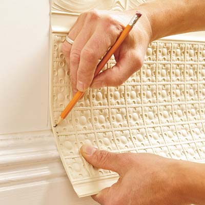 using a pencil to mark the height of the baseboard molding in order to fit the bottom of the Lincrusta wainscot panel
