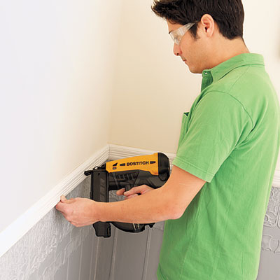 installing the chair rail molding to cap off the newly-installed Lincrusta wainscot panels with a pneumatic brad nailer
