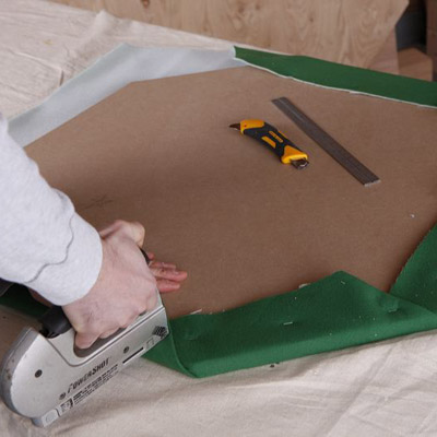 two men attaching felt to poker table