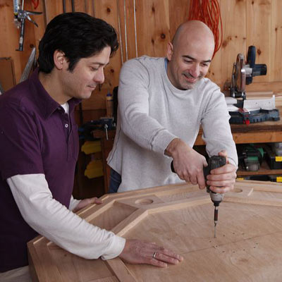 two men attaching collar to poker table