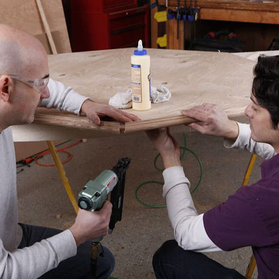 men trimming the lid of poker table