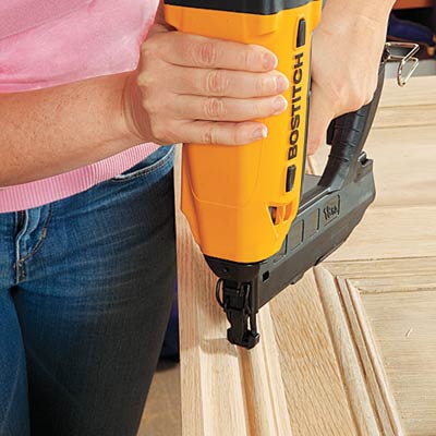 securing crown to the repurposed door to make the top of the headboard with a brad nailer