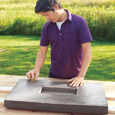 Mark Powers runs a scrap block of wood over hypertufa tabletop to soften rough spots and scrape away leftover foam
