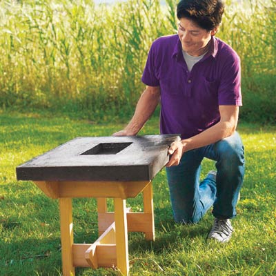Mark Powers positions the hypertufa tabletop on top of the table frame