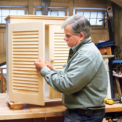 Tom Silva attaches the knobs to the shutter doors