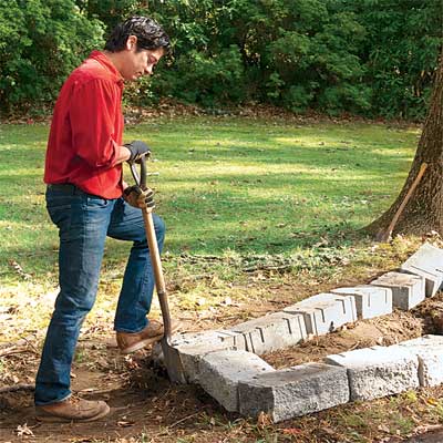 person using stones to make a rough outline to build a stone planter