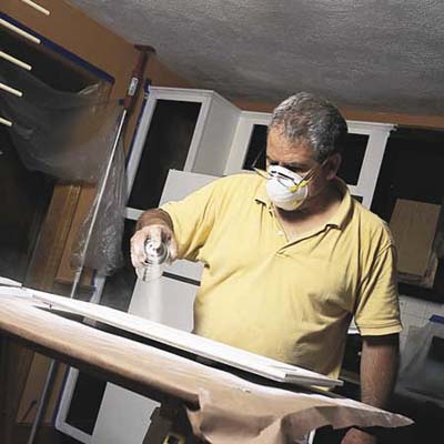 John Dee sprays a fast-dry primer on spots with spackle or bare wood from sanding