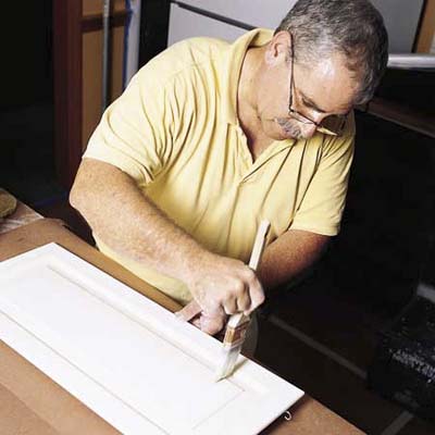John Dee applying the finish coat to a cabinet door