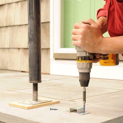 person drilling brackets into porch