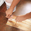 using a putty knife to lift up edges of vinyl flooring patch area