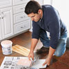 spreading adhesive on a patch of vinyl flooring with a V-notch trowel