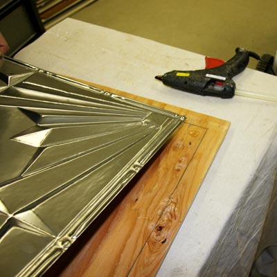 applying the tin-tile to the plywood frame with hot-glue