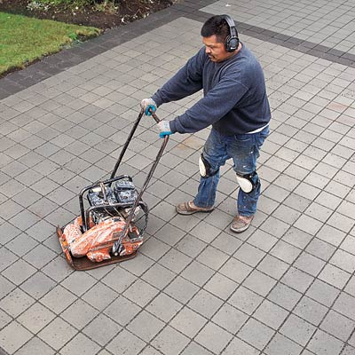 tamping the permeable-pavers with a plate compactor for a new driveway
