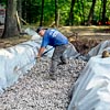 man digging trench for building a fieldstone wall