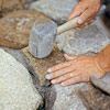lining up and hammering in stones for building a fieldstone wall