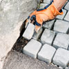 filling gaps with trimmed cobblestones at the edge of a driveway apron