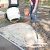spreading grout onto a cobblestone driveway apron with a squeegee