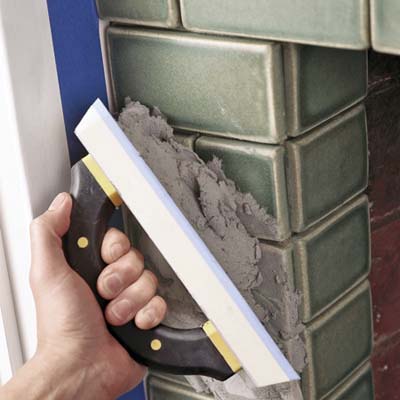 photo of tile being grouted with a grout float