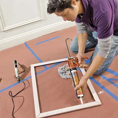 Using a caulk gun, apply panel adhesive to the four sides of the frame