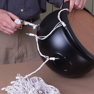 thread string lights through hole in cauldron for witch's cauldron halloween project