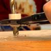 pliers hold a plastic endcap while a drill bit bores a hole in the cap