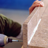 Drive screws through the pilot holes to secure the backsplash