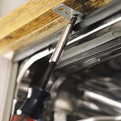 Screws are drawn in the mounting brackets to fasten dshwasher underside of the countertop 