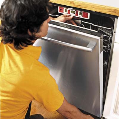 man fixing the dishwasher under the cabinet