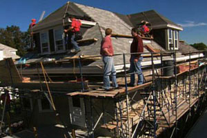 Norm Abram and Kevin O'Connor on scaffolding near the roof of the East Boston house project
